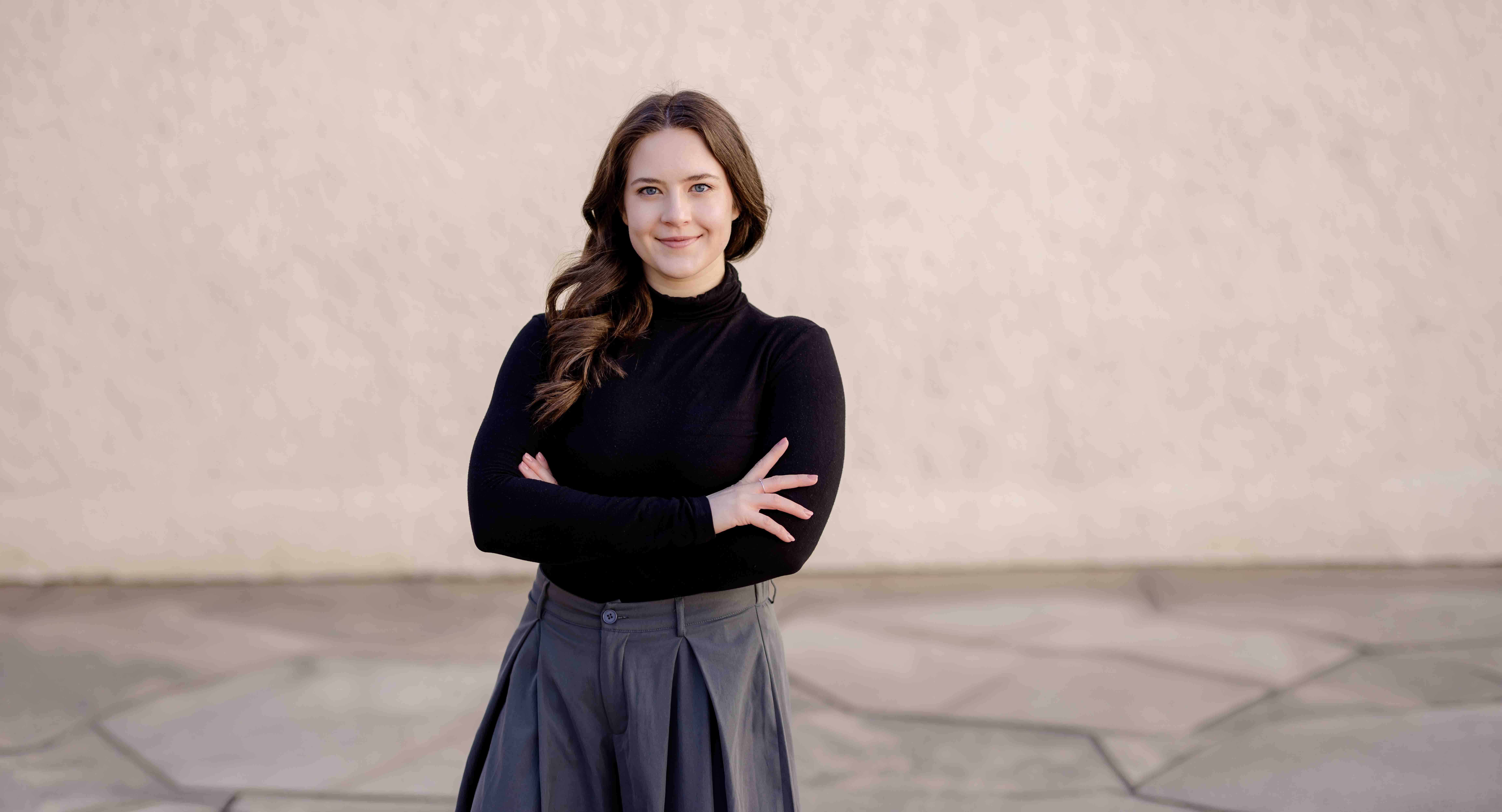 Authentisches Bewerbungsfoto einer jungen Frau mit leichtem Lächeln, schwarzem Oberteil und neutralem Hintergrund – professionell und natürlich aufgenommen - Bewerbungsfotos Freiberg - Bewerbungsbilder