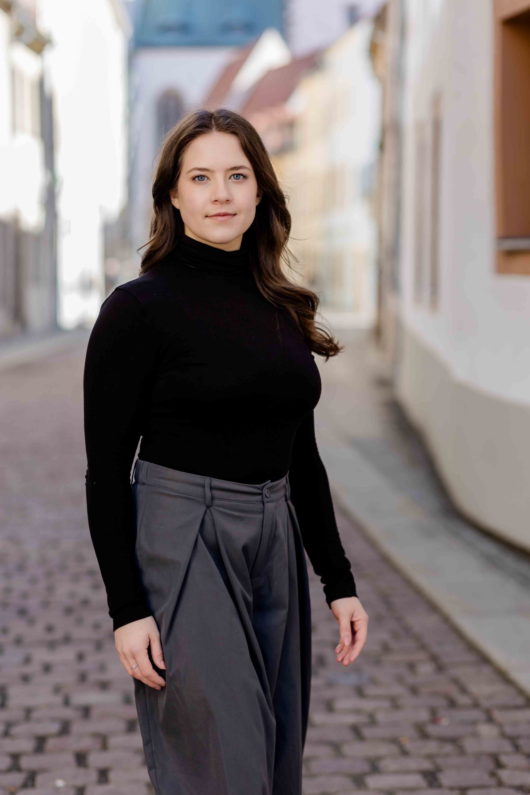 Authentisches Bewerbungsfoto einer jungen Frau mit leichtem Lächeln, schwarzem Oberteil und neutralem Hintergrund – professionell und natürlich aufgenommen - Bewerbungsfotos Freiberg - Bewerbungsbilder