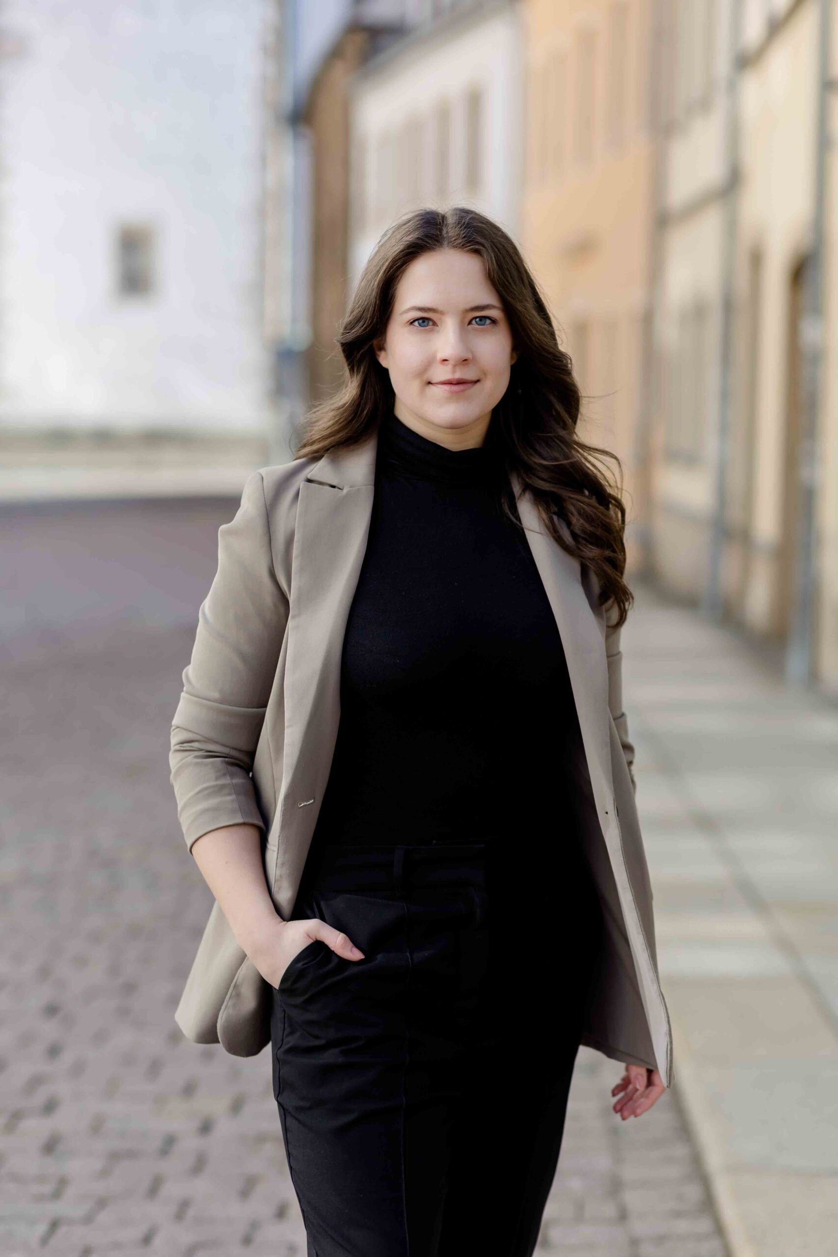 Authentisches Bewerbungsfoto einer jungen Frau mit leichtem Lächeln, schwarzem Oberteil und neutralem Hintergrund – professionell und natürlich aufgenommen - Bewerbungsfotos Freiberg - Bewerbungsbilder