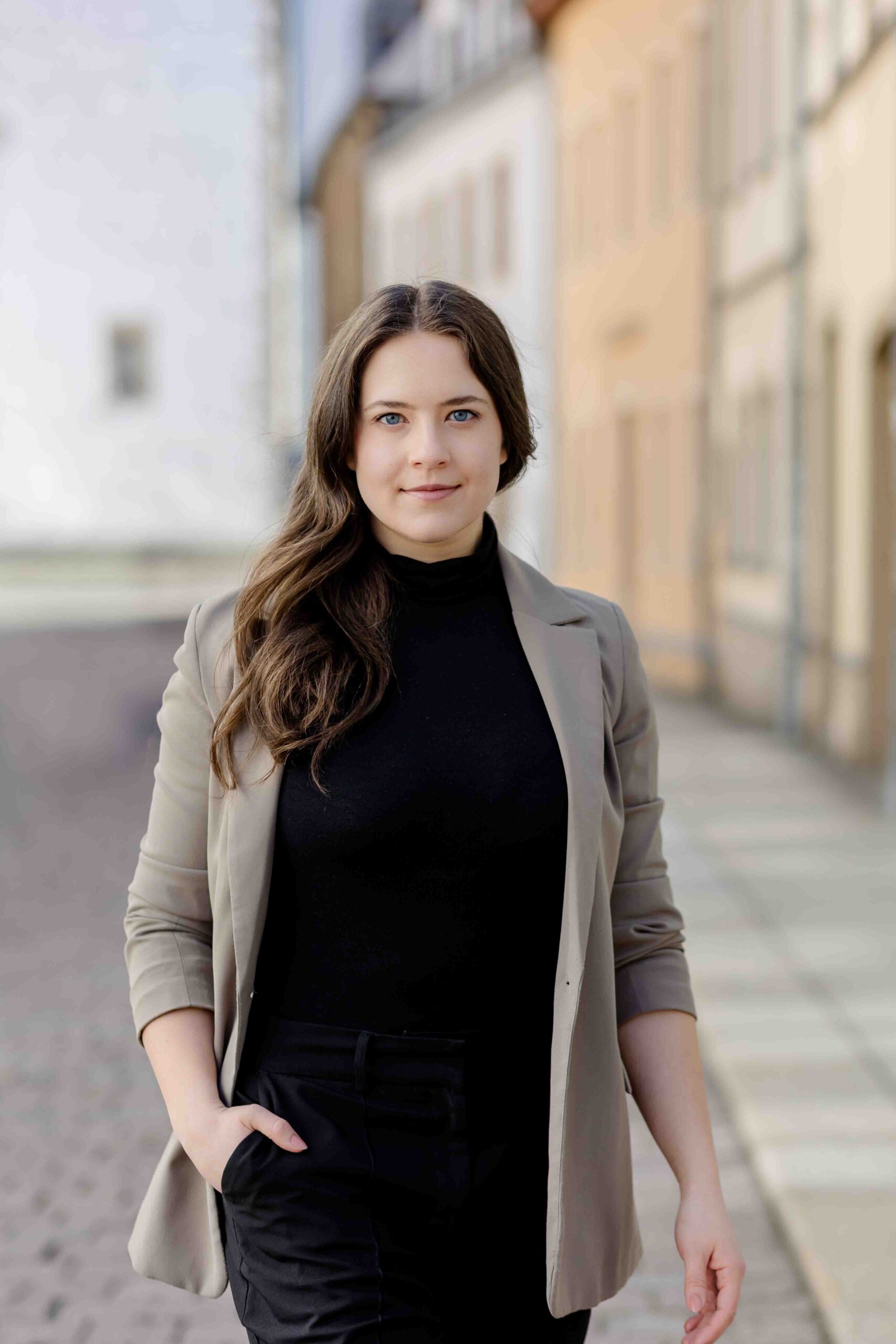 Authentisches Bewerbungsfoto einer jungen Frau mit leichtem Lächeln, schwarzem Oberteil und neutralem Hintergrund – professionell und natürlich aufgenommen - Bewerbungsfotos Freiberg - Bewerbungsfotos Freiberg