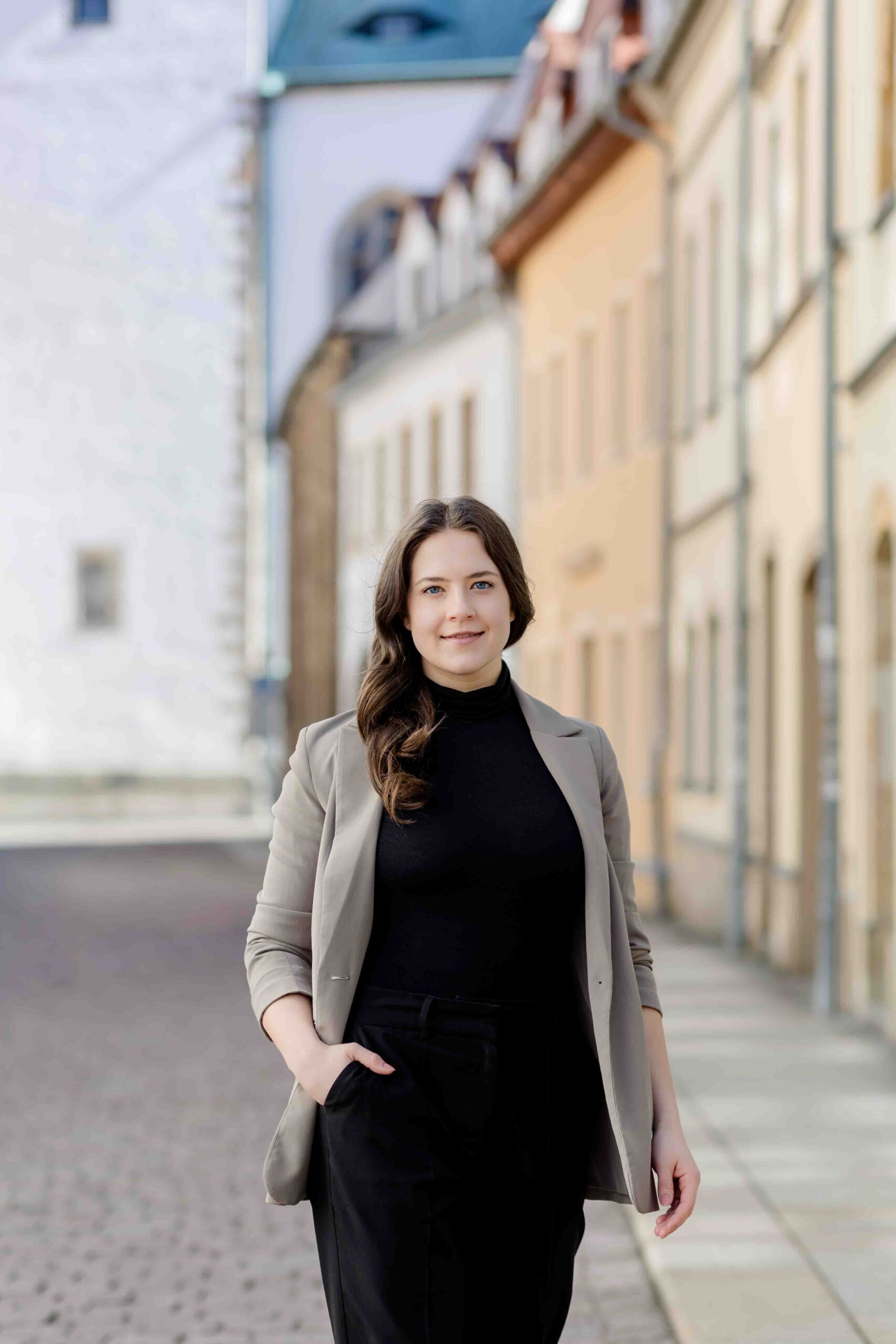 Authentisches Bewerbungsfoto einer jungen Frau mit leichtem Lächeln, schwarzem Oberteil und neutralem Hintergrund – professionell und natürlich aufgenommen - Bewerbungsfotos Freiberg - Bewerbungsfotos Freiberg