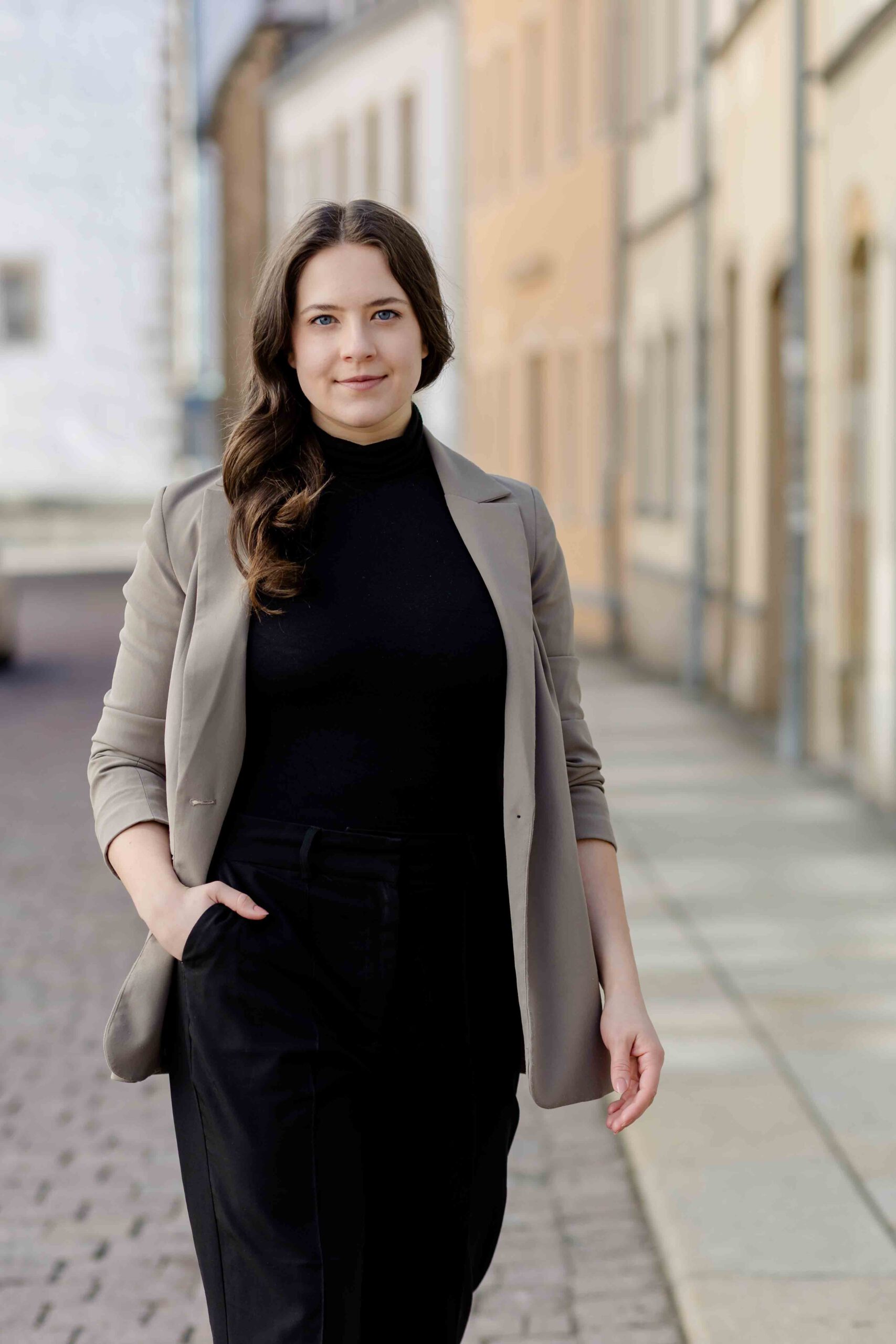 Authentisches Bewerbungsfoto einer jungen Frau mit leichtem Lächeln, schwarzem Oberteil und neutralem Hintergrund – professionell und natürlich aufgenommen - Bewerbungsfotos Freiberg - Bewerbungsfotos Freiberg