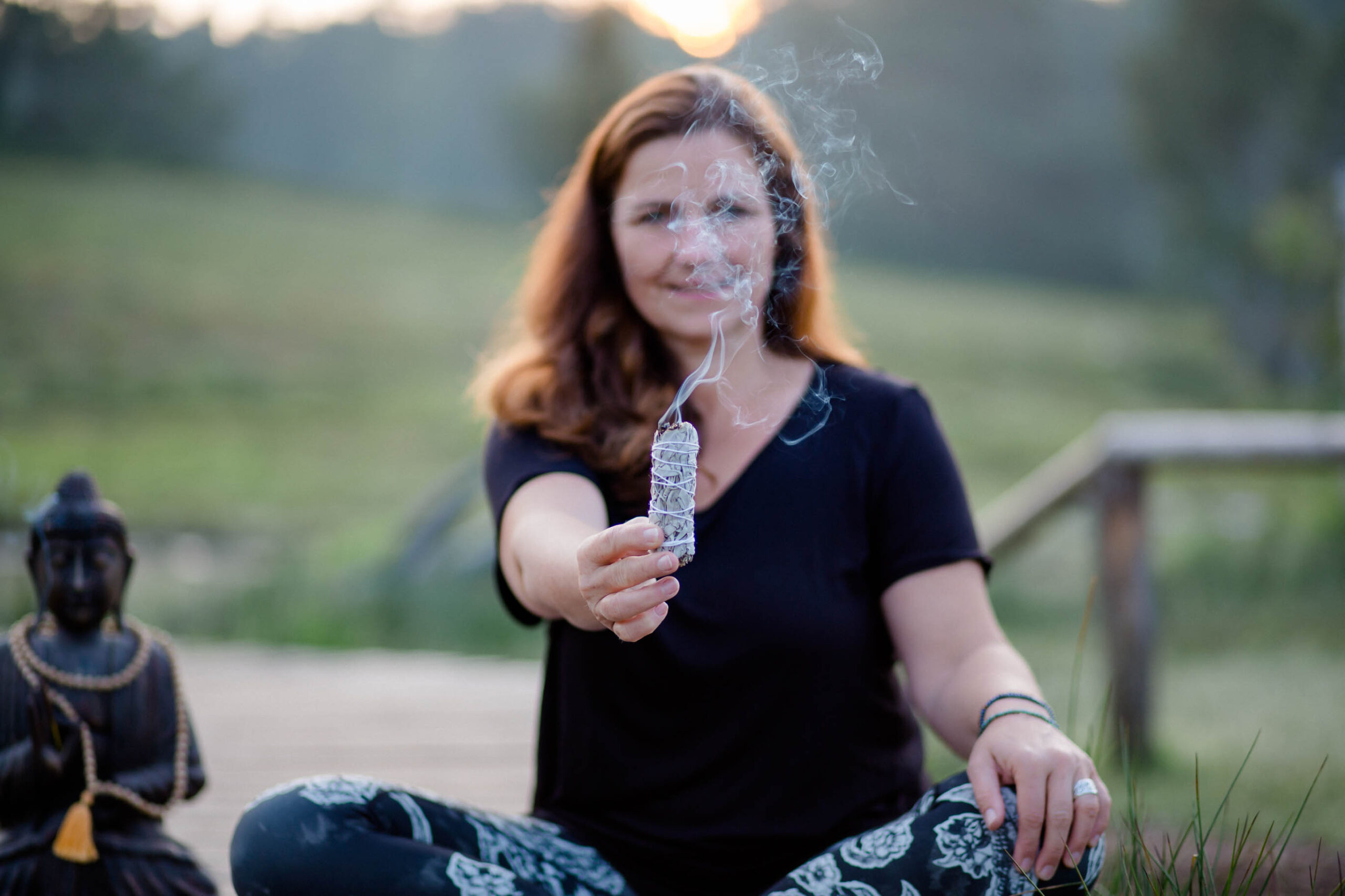 Businessfotos Yoga: Detailaufnahme von brennendem Räucherbündel in der Hand, ruhige Stimmung und weiches Licht im Hintergrund