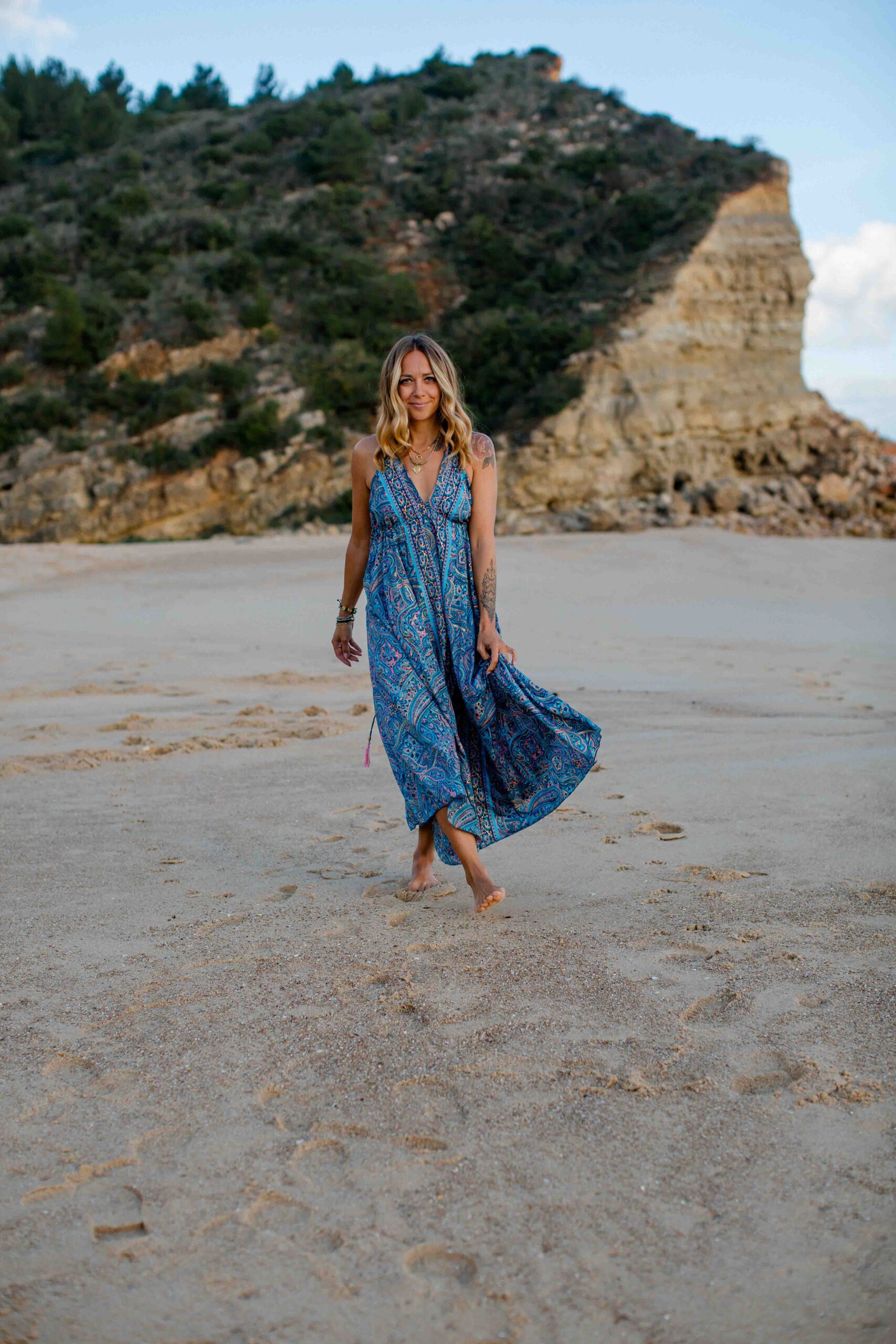 Frau im blauen Kleid läuft durch den Sand