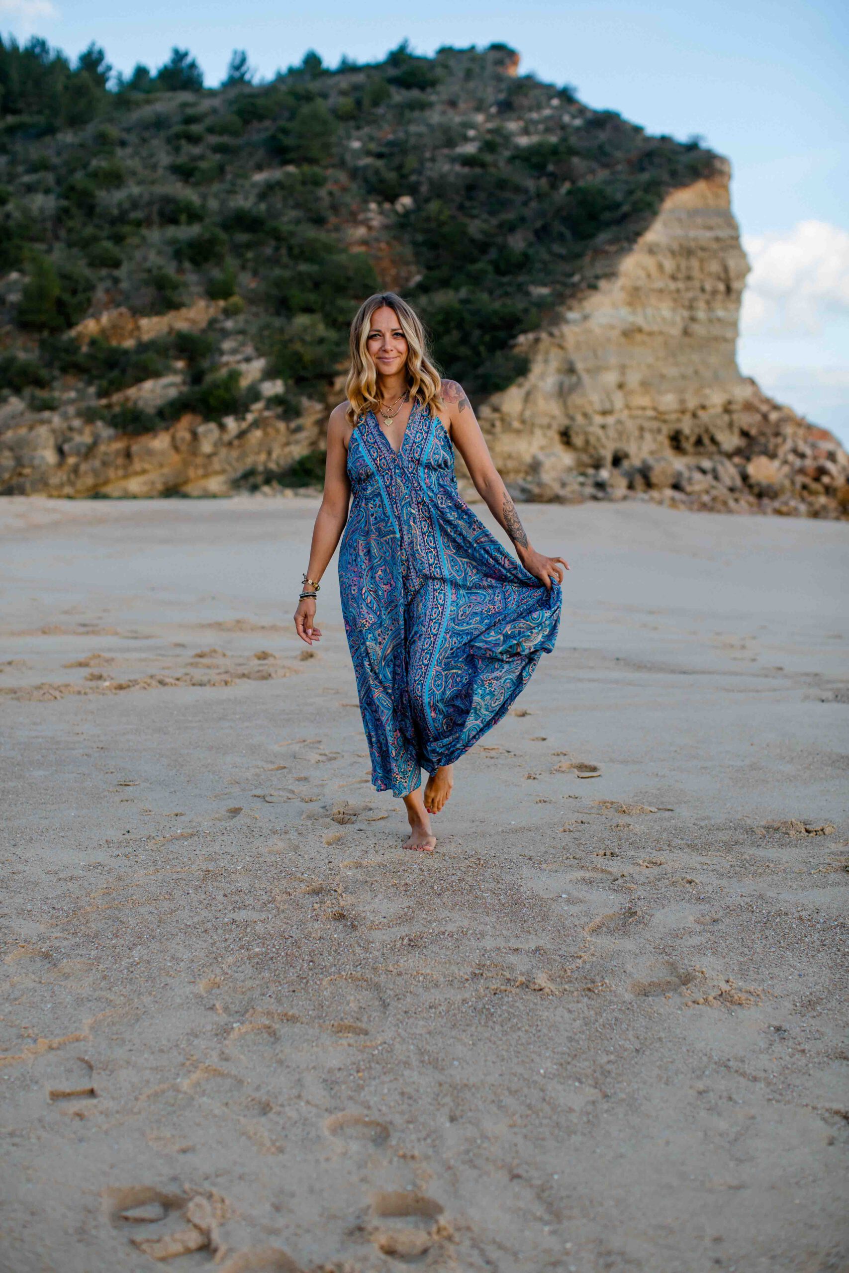 Frau im blauen Kleid läuft durch den Sand