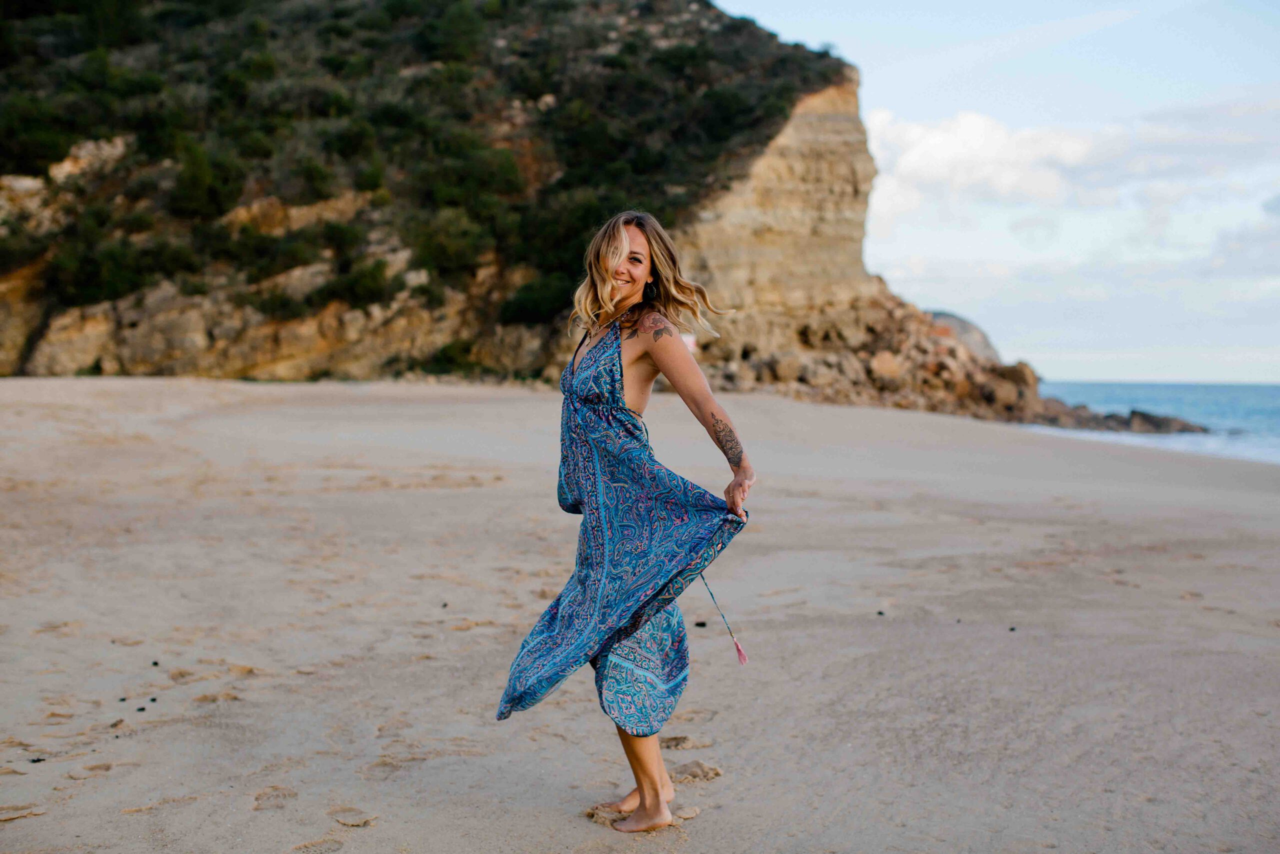Frau im blauen Kleid läuft durch den Sand