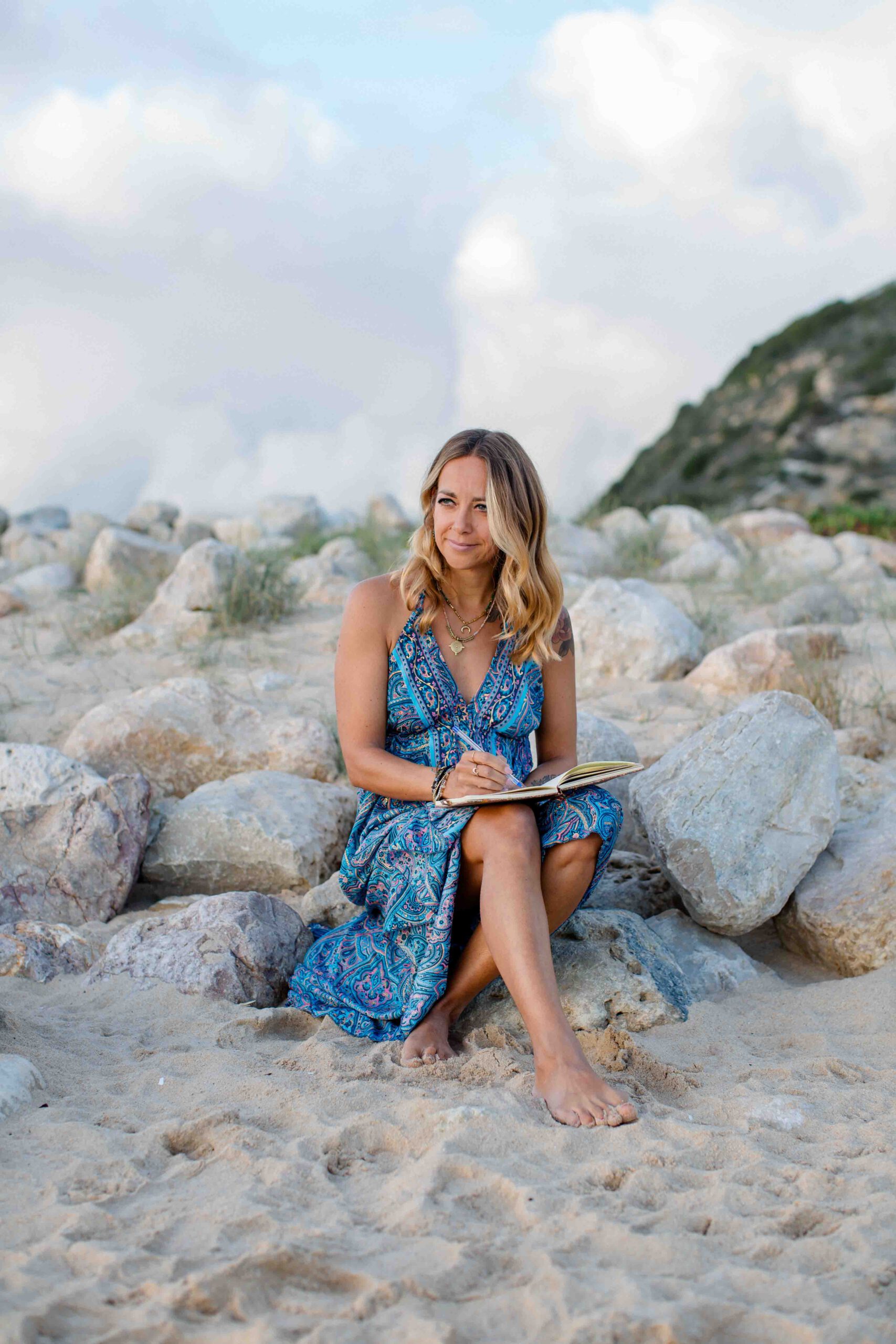 Frau im blauen Kleid mit Buch am Strand