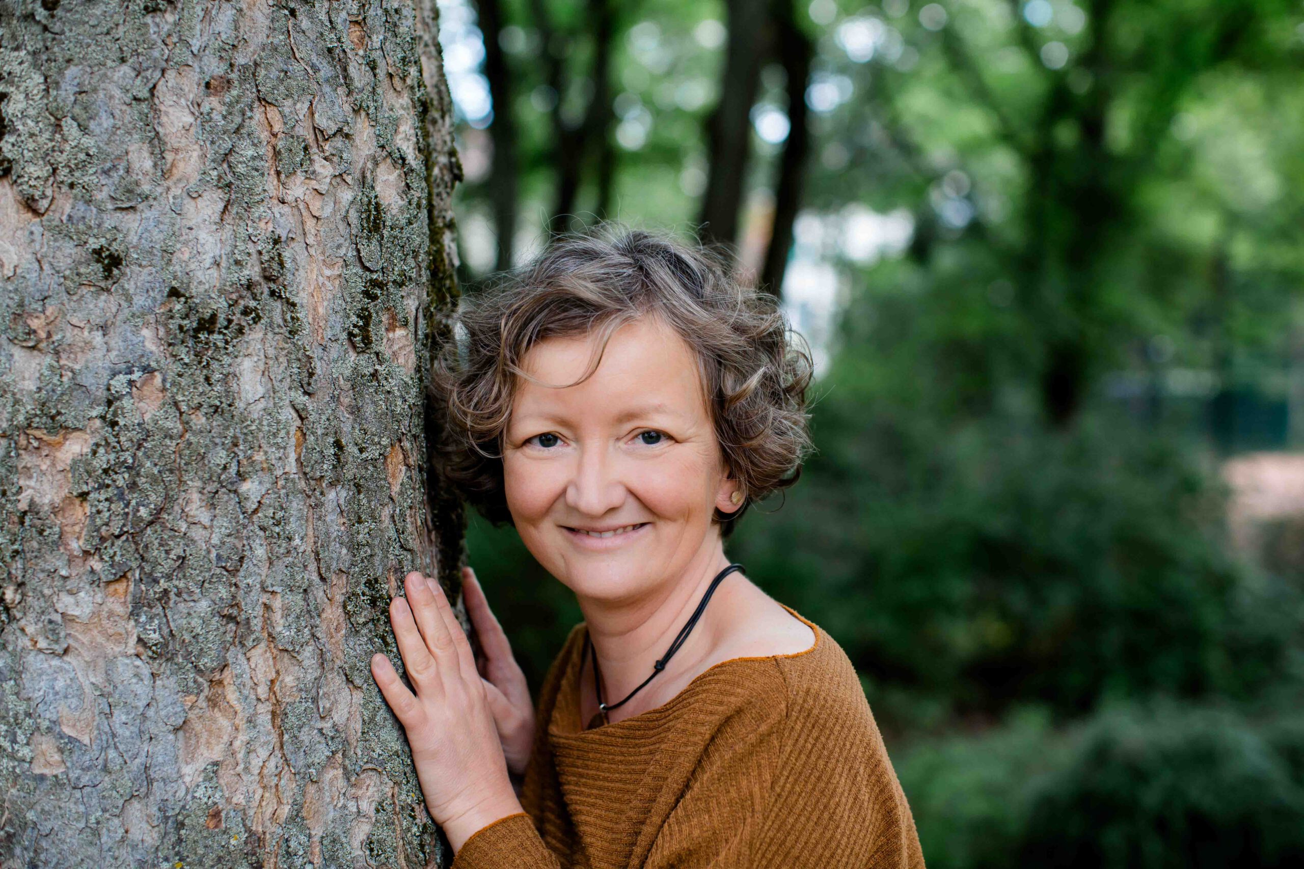 Frau steht an einem Baum - naturnah