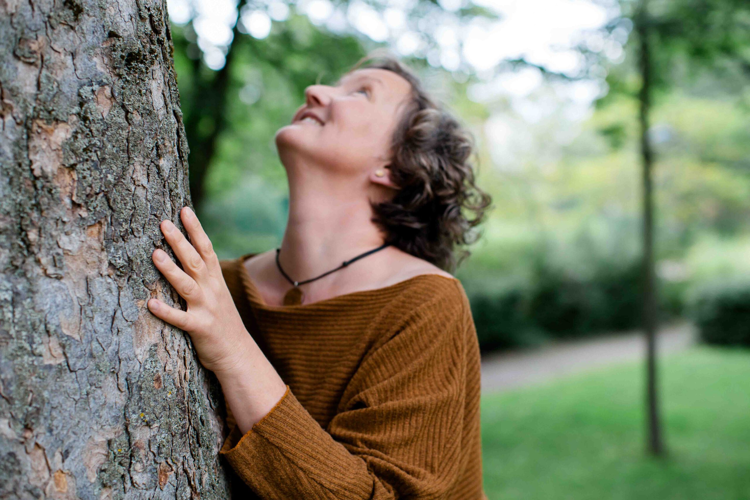 Frau steht an einem Baum - naturnah