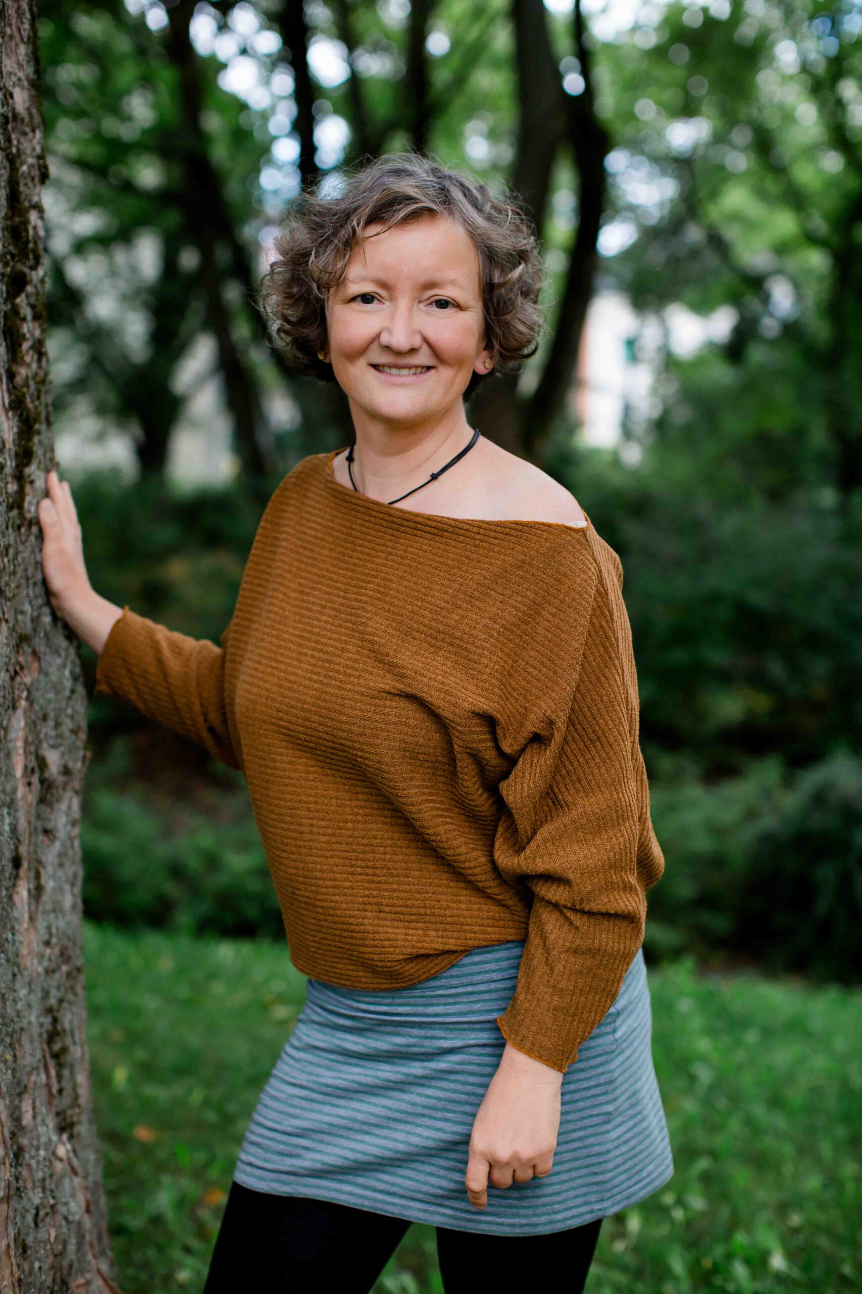 Frau steht an einem Baum - naturnah - Imagefilm für Therapeuten