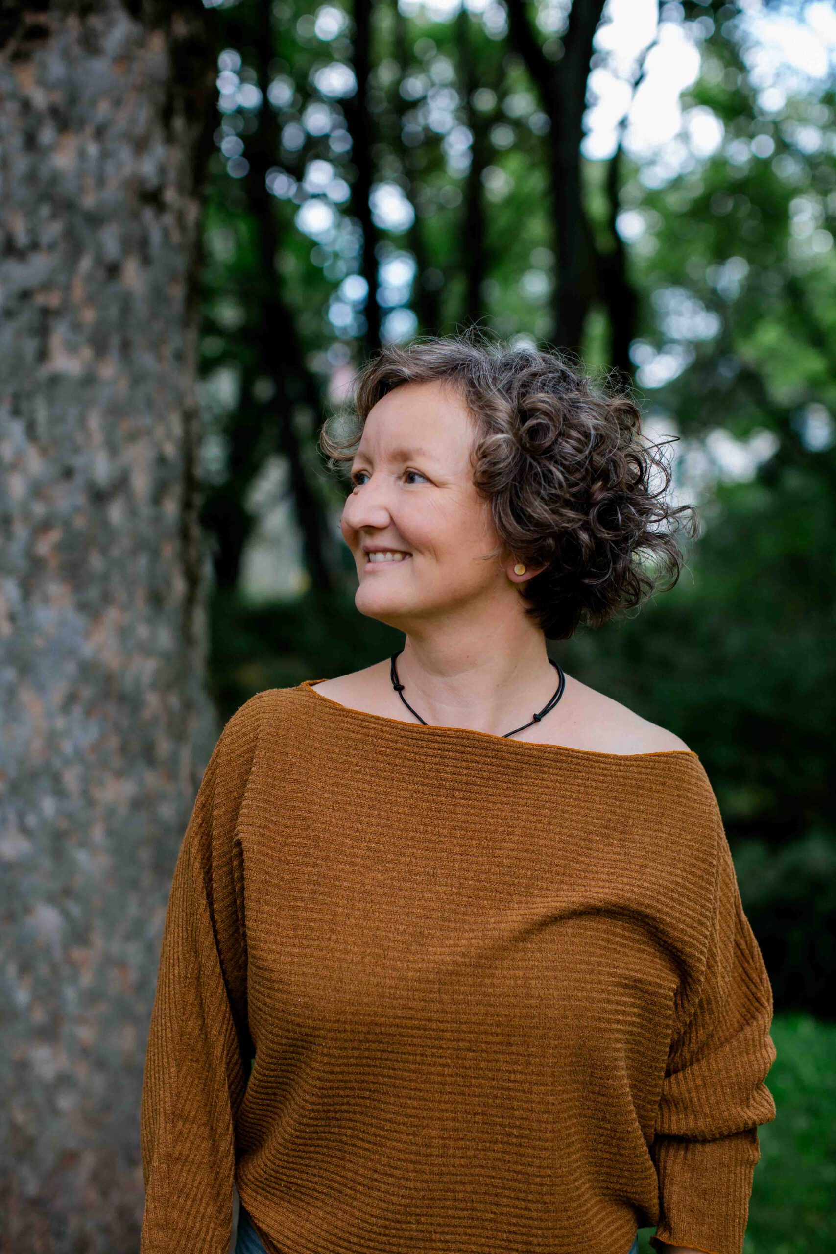 Frau steht an einem Baum - naturnah - Imagefilm für Therapeuten